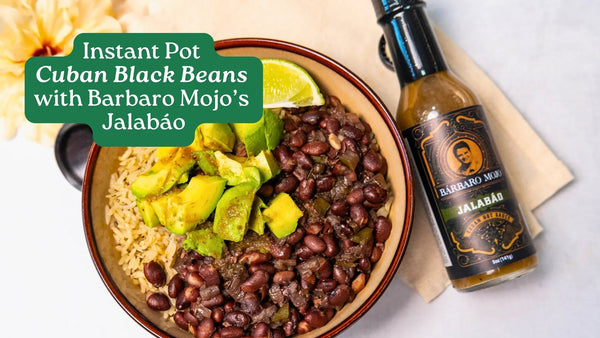 Bowl of Cuban black beans over rice with avocado and lime, next to a bottle of Barbaro Mojo Jalabáo
