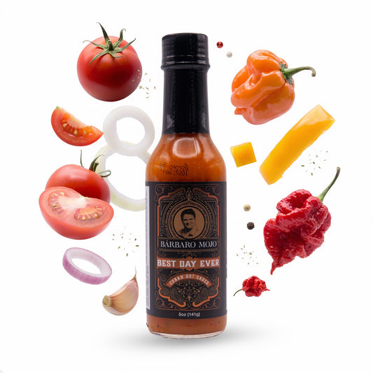 Barbaro Mojo Best Day Ever bottle surrounded by mango, tomato, orange habanero and a Carolina Reaper