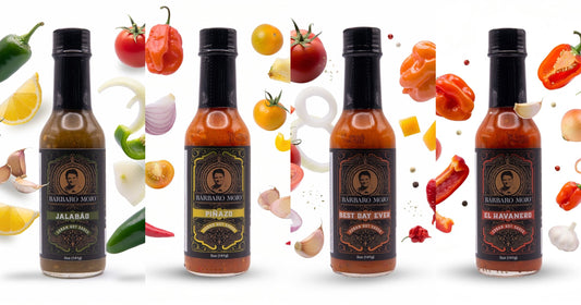 Four Barbaro Mojo bottles, Jalabáo, Piñazo, Best Day Ever and El Havanero, each surrounded by the fresh peppers, vegetables and fruit that go into it