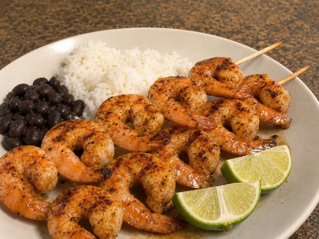 Grilled El Havanero mojo shrimp skewers on a plate with white rice, black beans, and lime wedges