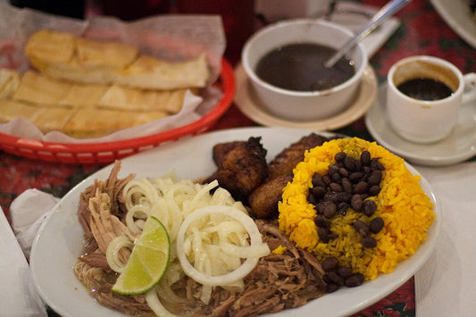 A Cuban plate: roast pork with onions, yellow rice and black beans, maduros, Cuban bread and cafecito