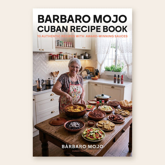 Cover of the Barbaro Mojo Cuban Recipe Book: a smiling grandmother cooking in a bright kitchen over a table of Cuban dishes, with three hot sauce bottles on the counter